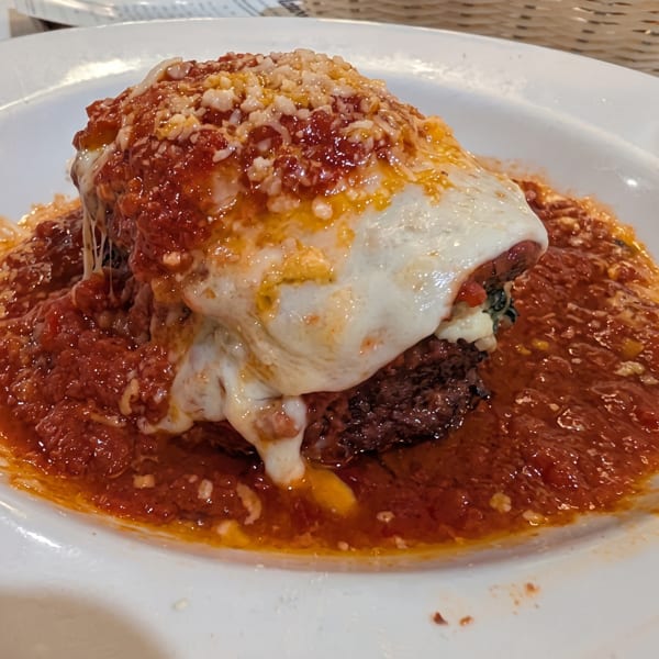 Close-up of a meatball parmigiana covered in melted mozzarella, marinara sauce, and grated cheese.